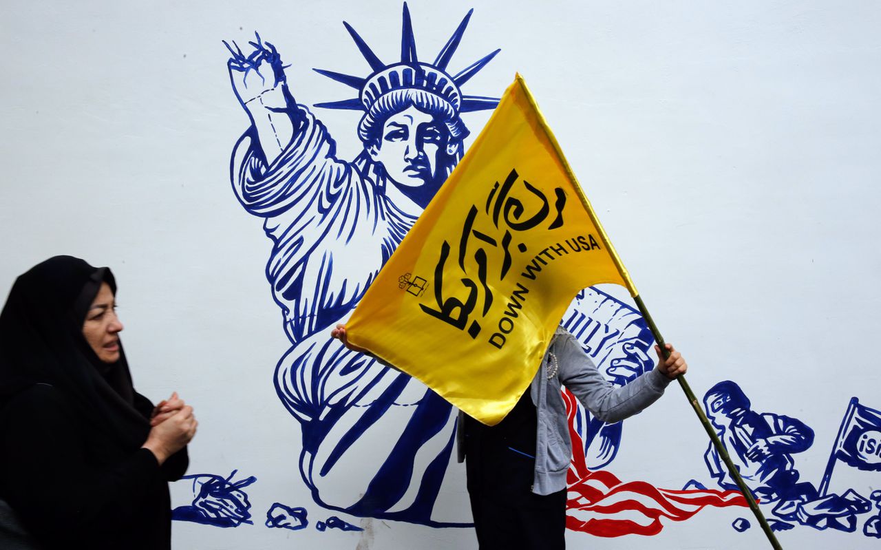Een Iraanse vrouw houdt een vlag vast met anti-Amerikaanse teksten, tegenover de voormalige Amerikaanse ambassade in Teheran, 4 november 2019.