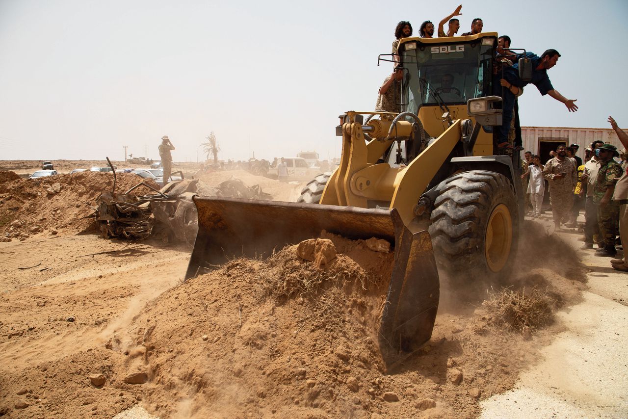 Een bulldozer schuift zand opzij op een ceremonie zondag ter gelegenheid van het heropenen van de kustweg tussen Oost en West, ten oosten van Misrata.