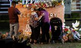 Mensen troosten elkaar bij de gedenkplaats voor de 21 slachtoffers die een 18-jarige schutter  vorige maand   maakte op een basisschool in Uvalde, Texas.