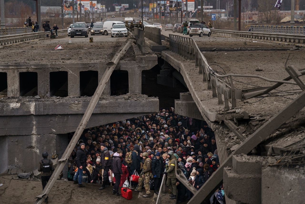 Oekraïners schuilen onder een verwoeste brug terwijl ze proberen de rivier de Irpin over te steken aan de rand van Kyiv, op 5 maart 2022.