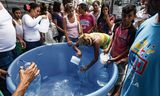Inwoners van Caracas vullen flessen water. Door de stroomstoring is er geen stromend water.