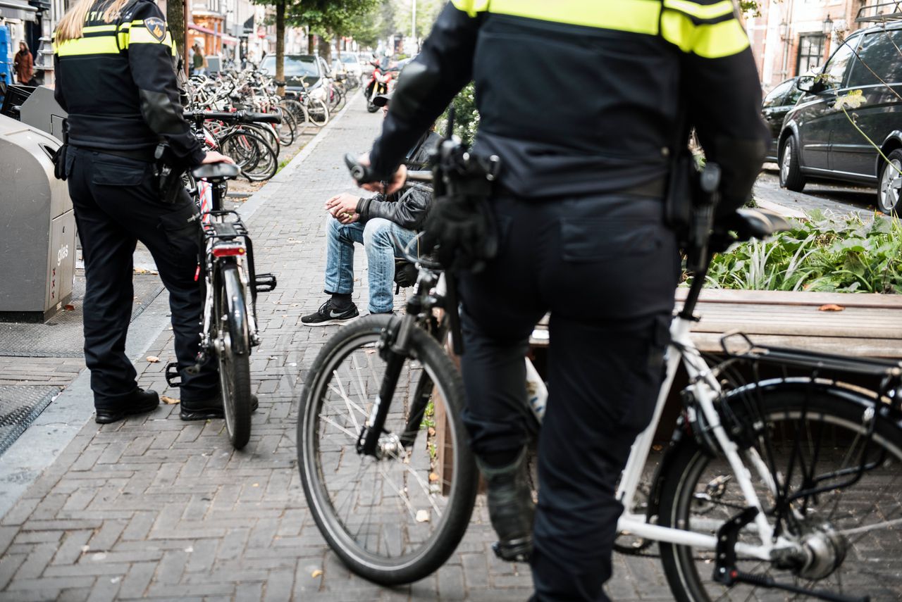 De politie praat met een man die alcohol in het openbaar drinkt op de Elandsgracht in Amsterdam
