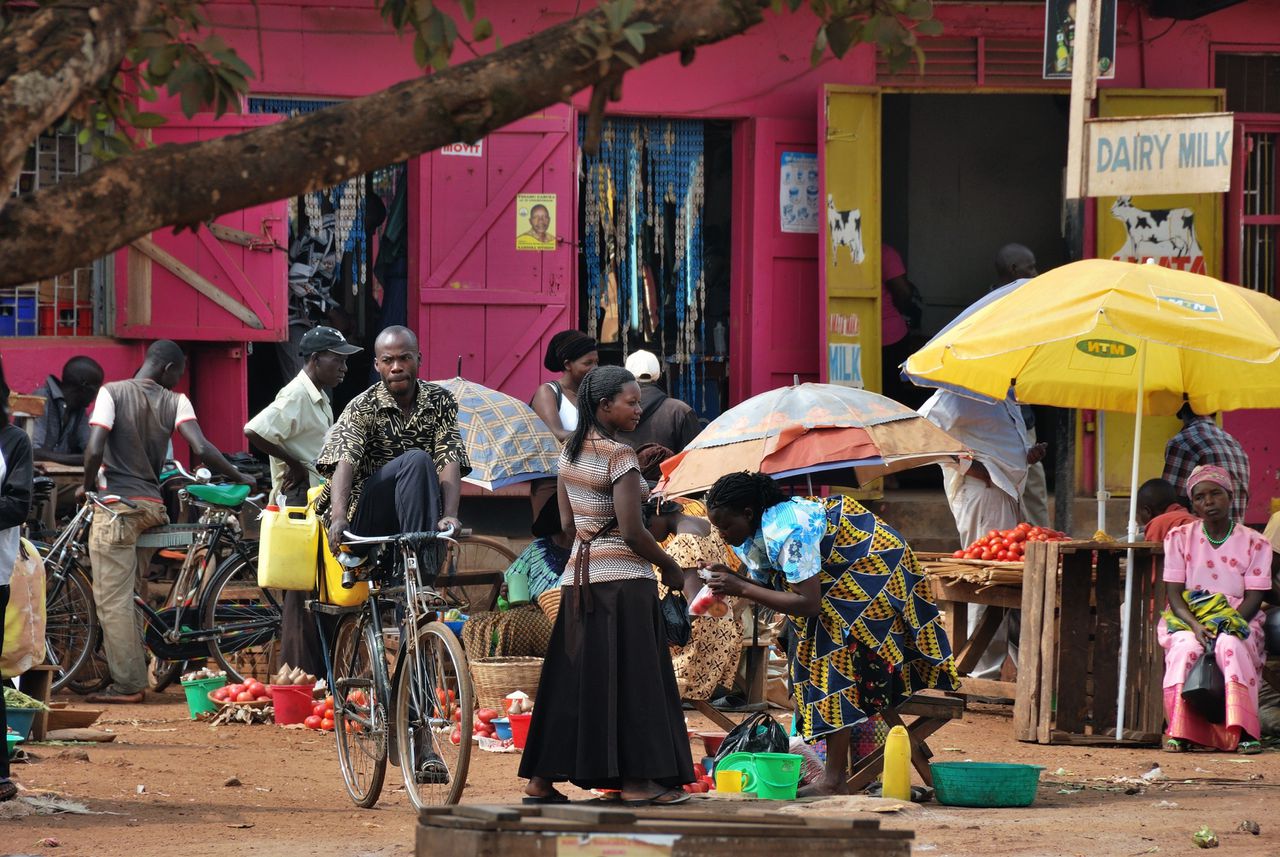 Mensen doen inkopen op een markt in Oeganda. Contant geld is het courante betaalmiddel.