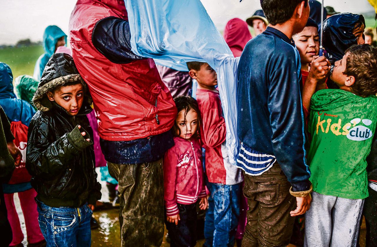 Kinderen wachten, op 9 april, in een rij vluchtelingen op voedsel in een kamp bij Idomeni, aan de Grieks-Macedonische grens. Daar bevinden zich nog steeds duizenden migranten, die niet kunnen worden uitgezet en niet formeel in Europa worden toegelaten.