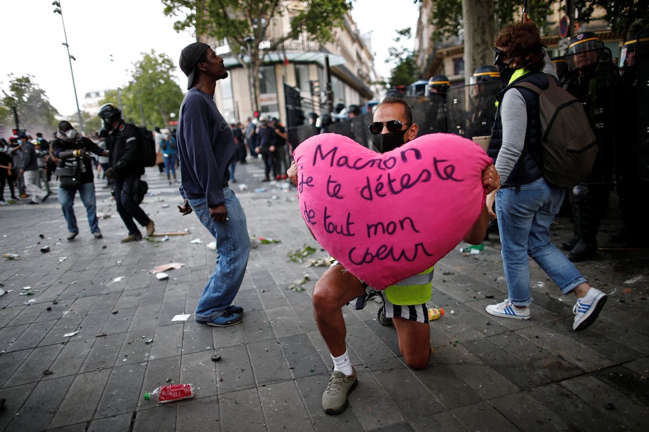 Een demonstrant in Parijs houdt een hart omhoog met de tekst ‘Macron, ik veracht je met heel mijn hart’