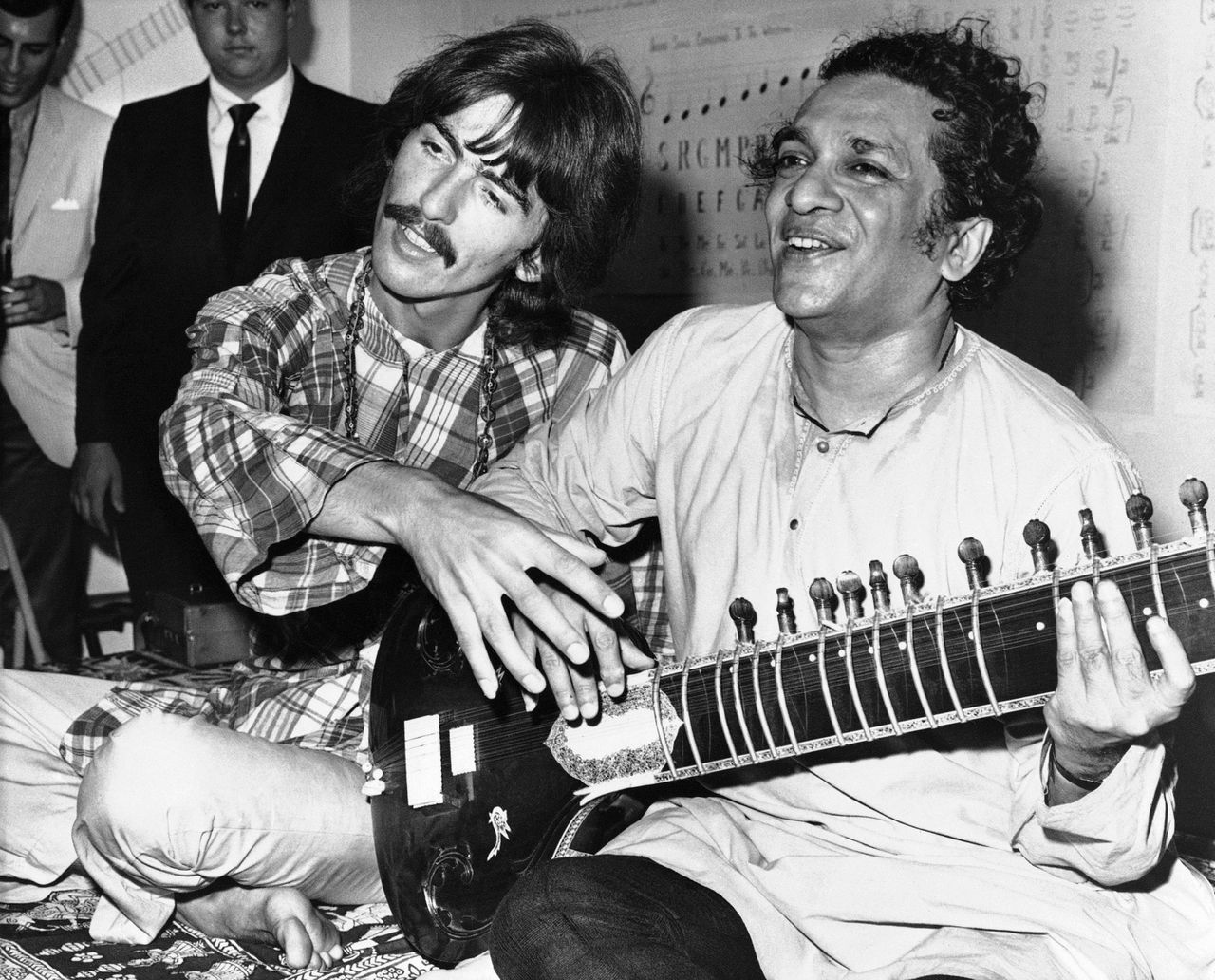 FILE - In this Aug. 3, 1967 file photo, George Harrison, of the Beatles, left, sits cross-legged with his musical mentor, Ravi Shankar of India, in Los Angeles, as Harrison explains to newsmen that Shankar is teaching him to play the sitar. Shankar, the sitar virtuoso who became a hippie musical icon of the 1960s after hobnobbing with the Beatles and who introduced traditional Indian ragas to Western audiences over an eight-decade career, died Tuesday, Dec. 11, 2012. He was 92. (AP File Photo)