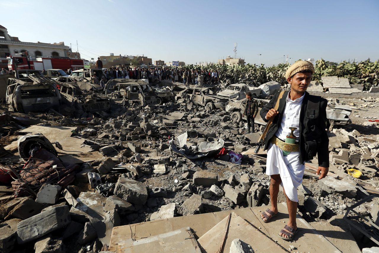 Een Houthi-rebel staat bij voertuigen die verwoest zouden zijn bij een Saoedische luchtaanval in Sana'a, de hoofdstad van Jemen.
