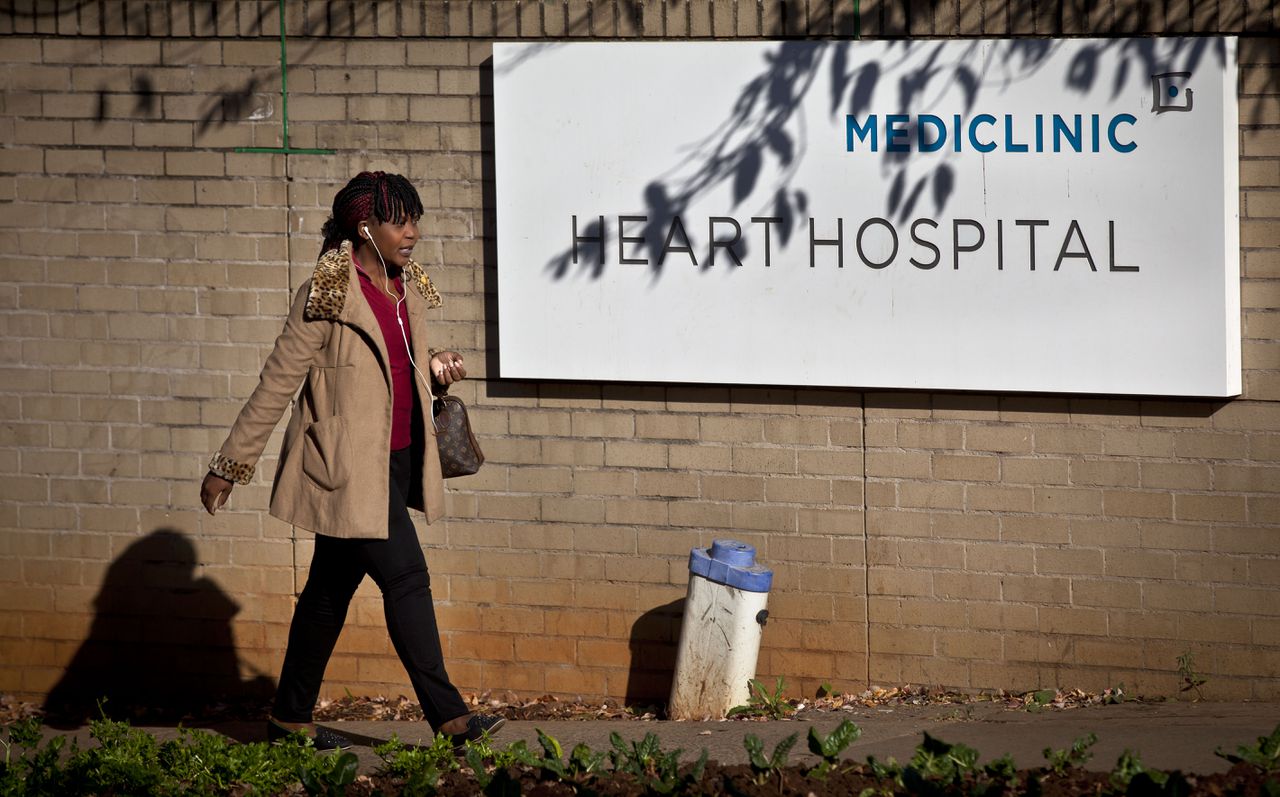 Een vrouw loopt langs het Mediclinic Heart Hospital in Pretoria, waar Nelson Mandela ligt.