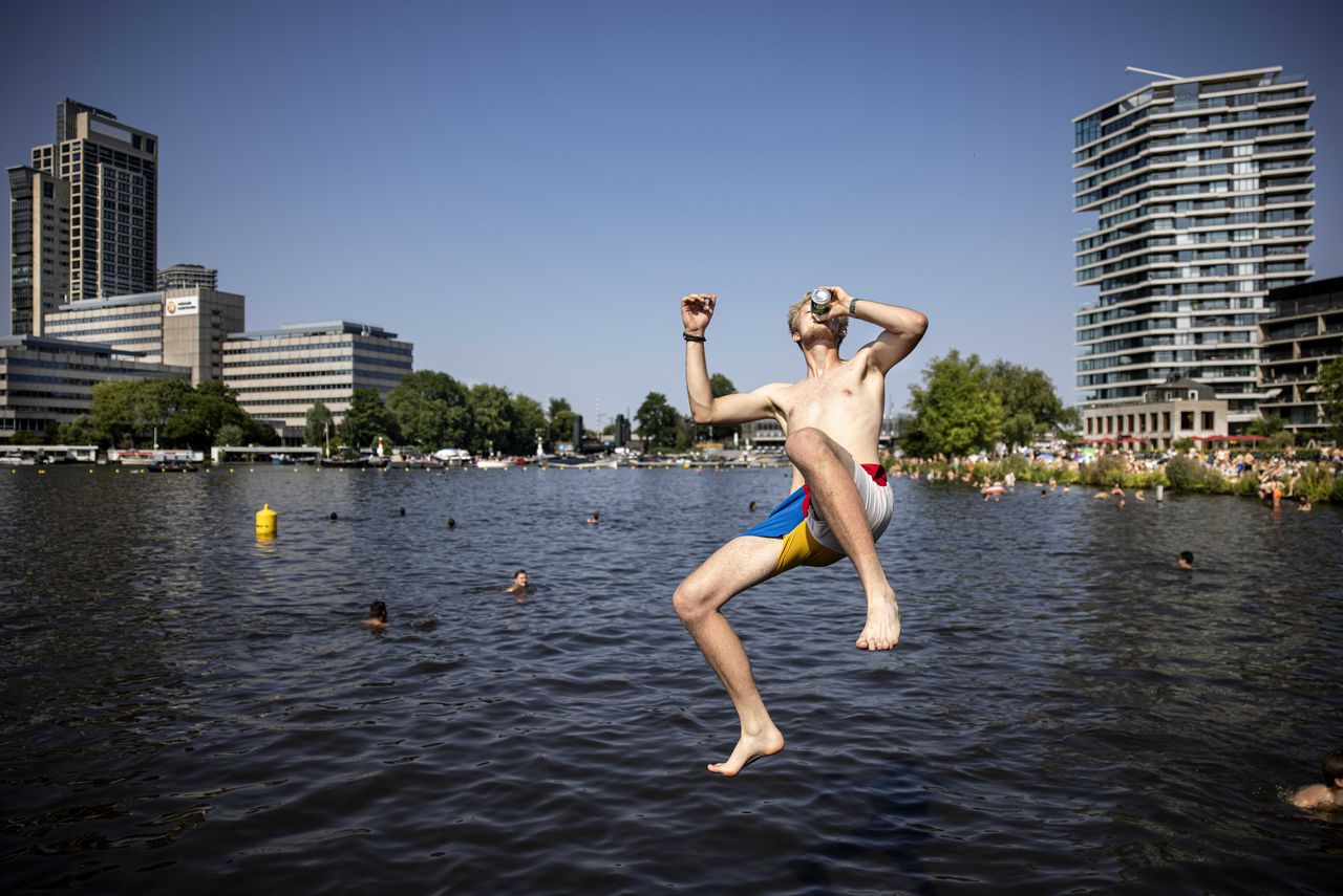 Mensen zoeken verkoeling tegen de hitte in het water, zo ook aan de Amstel.