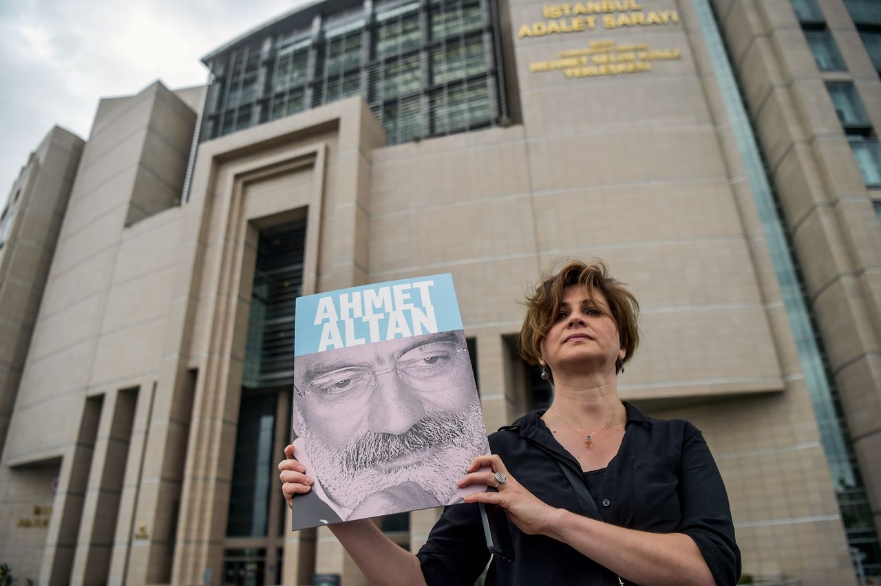 Een journalist houdt een foto van de Ahmet Altan voor een rechtbank in Istanbul.