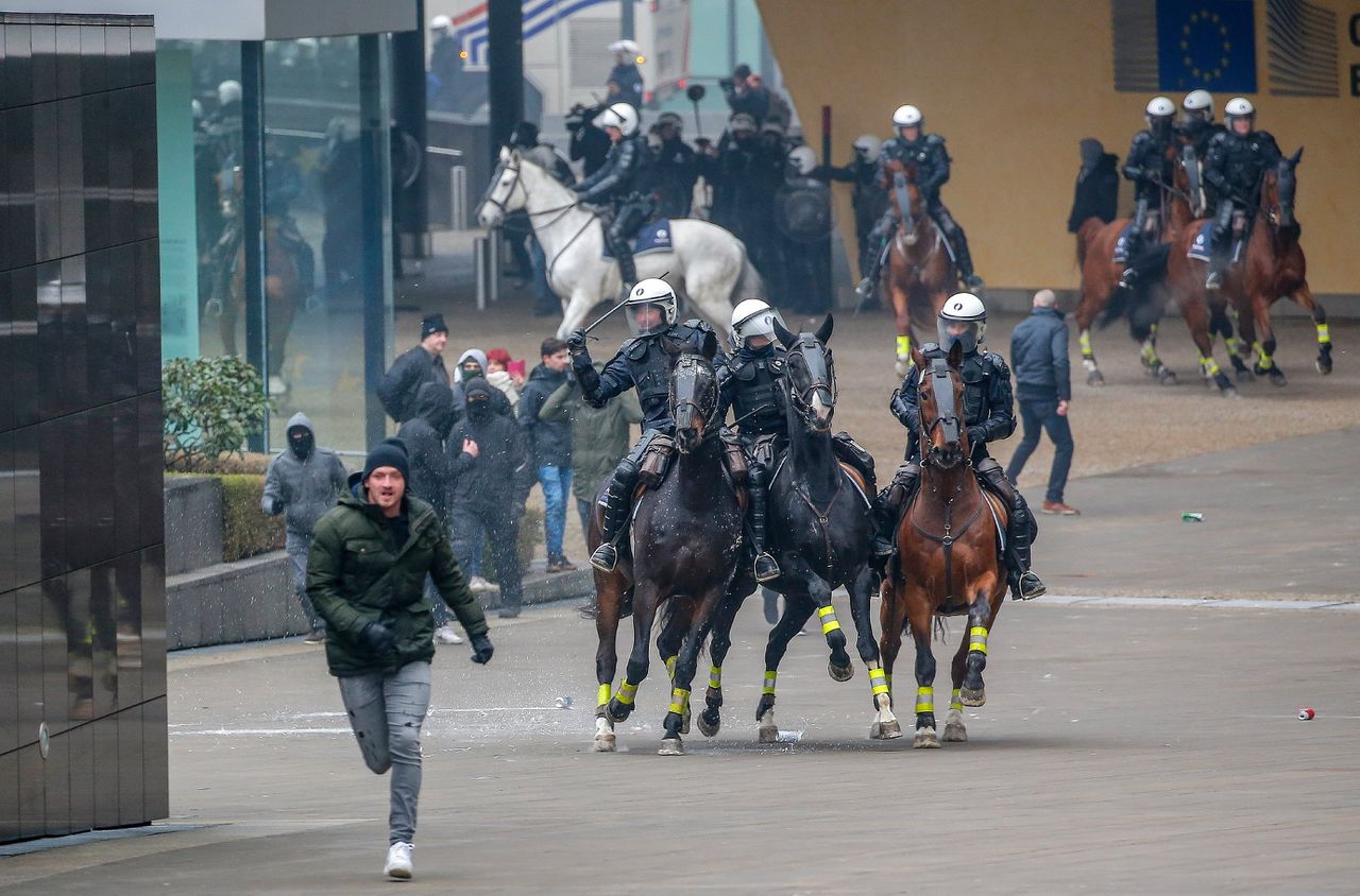 Agenten te paard achtervolgen demonstranten in de Europese wijk van Brussel, nadat een manifestatie tegen ‘Marrakesh’ uit de hand is gelopen. Foto EPA