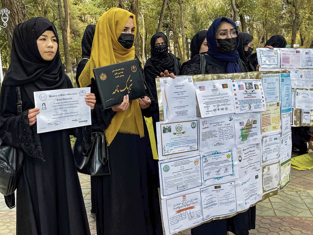 Afghaanse vrouwen demonstreren voor baankansen, met hun opleidingspapieren als protestbanners.