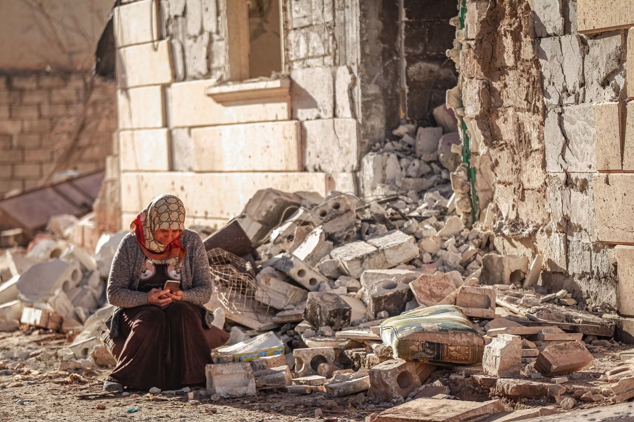 Een vrouw in Jindires, in het noordwesten van Syrië vlak bij de Turkse grens, zit tussen de restanten van een ingestort huis.