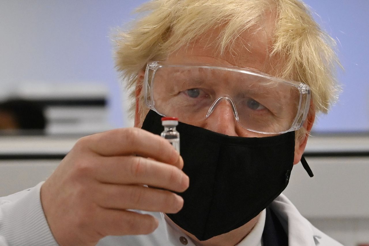 Premier Boris Johnson poseert met een flesje van het vaccin van AstraZeneca en Oxford.