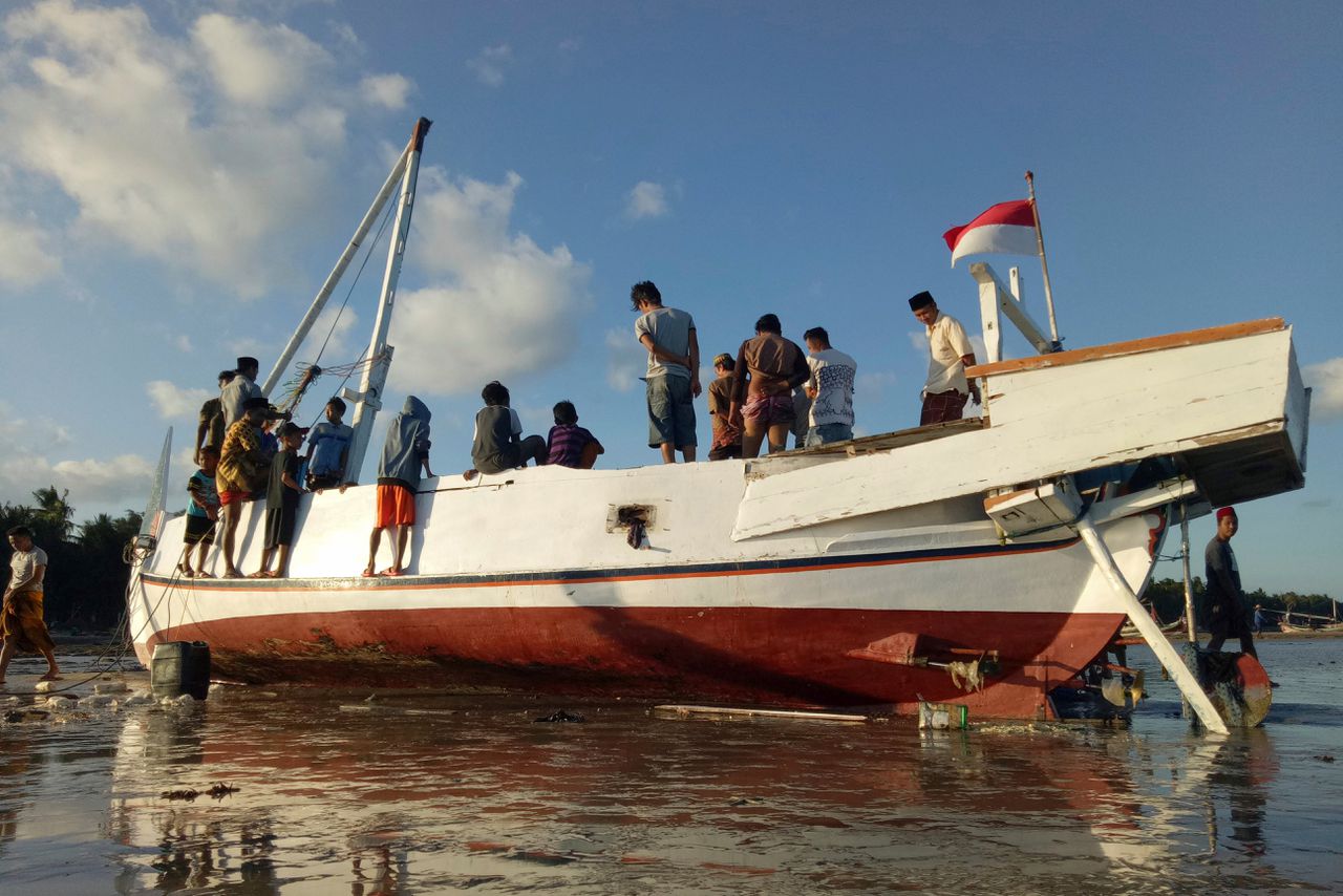 Mensen inspecteren het wrak van de boot Arim Jaya die voor de kust van Java omsloeg.