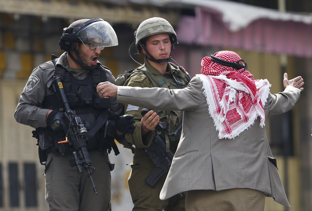 Een Palestijn en twee Israëlische agenten in Hebron op de Westelijke Jordaanoever. Daar kwam het vandaag tot rellen.