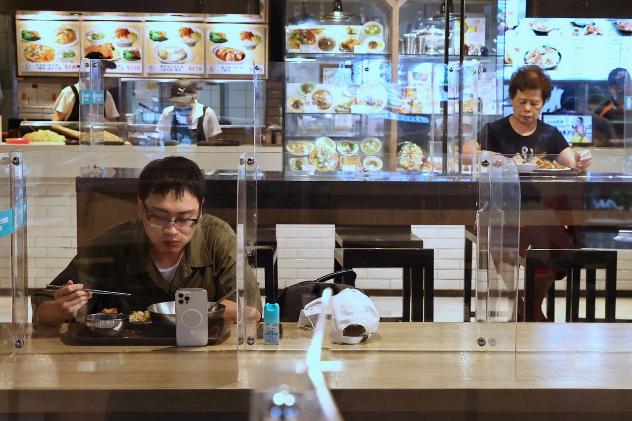 Mensen in Taiwan eten in een cafetaria tussen plastic schermen vanwege de coronacrisis.