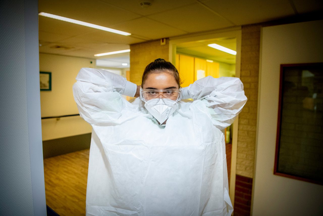 Een medewerker van een zorgcentrum met beschermende kleding.