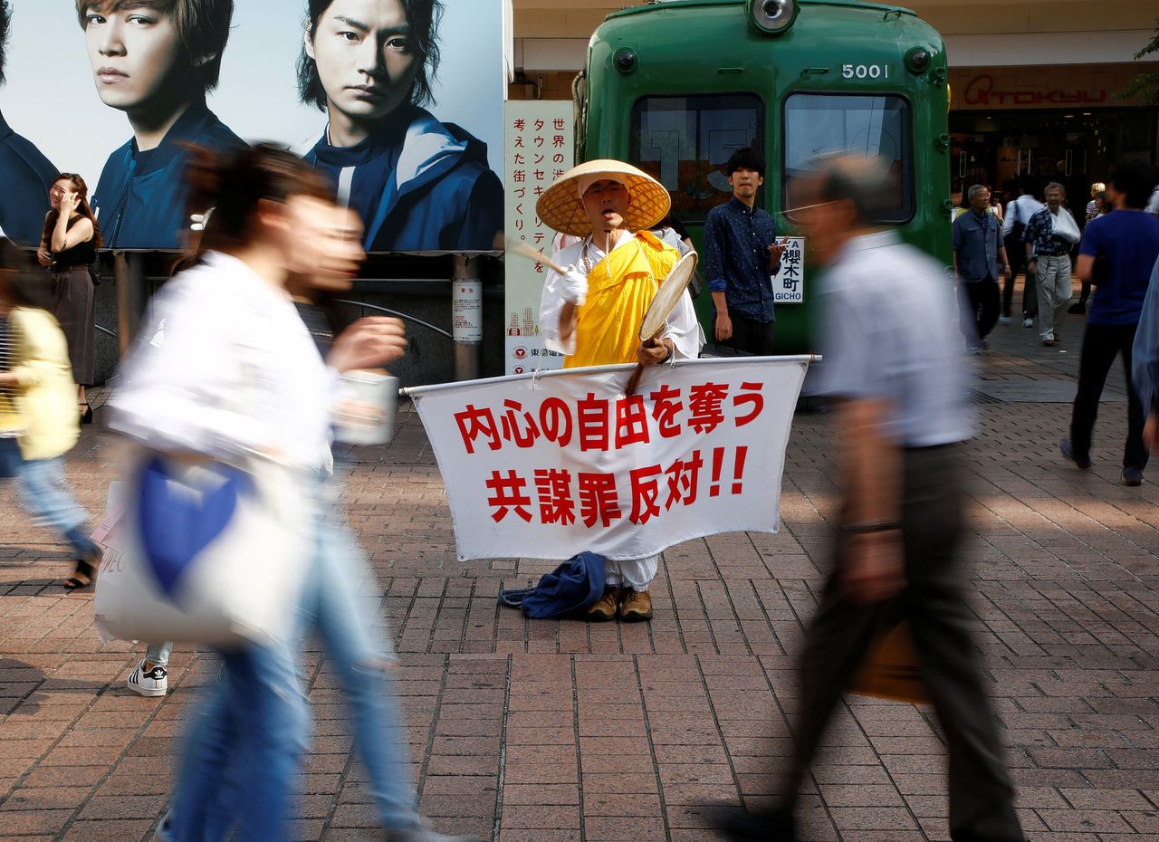 Een monnik demonstreert tegen de voorgenomen anti-terreurmaatregelen, bij het treinstation Shibuya in Tokio. Op zijn spandoek staat: "Kom in verzet tegen de nieuwe samenzweringswet, die geestelijke vrijheid inperkt."
