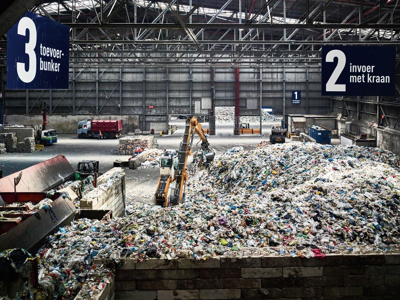 Een kraan grijpt in de hopen plastic in de ryclingfabriek Suez in de Rotterdamse Waalhaven.