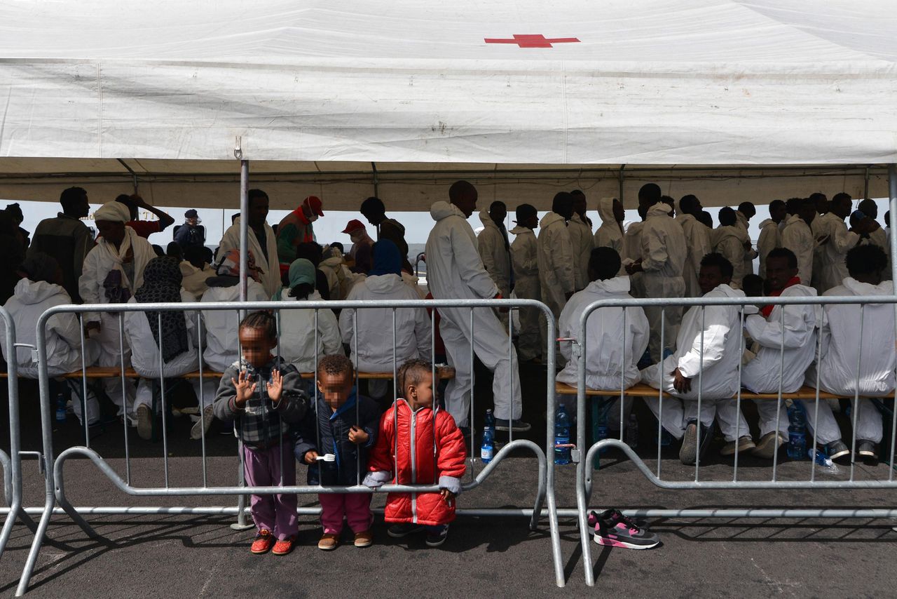 Migranten wachten onder een tent in de haven van Salerno vlak nadat ze zijn gered door de Italiaanse kustwacht.