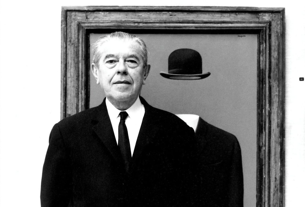 René Magritte voor een van zijn schilderijen.