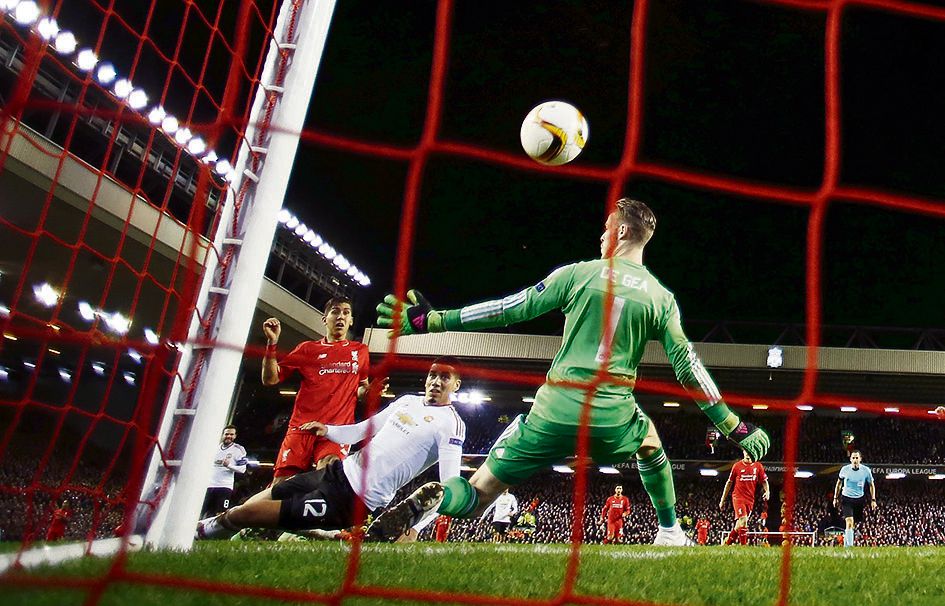 Roberto Firmino (in het rood) schiet de 2-0 achter doelman De Gea