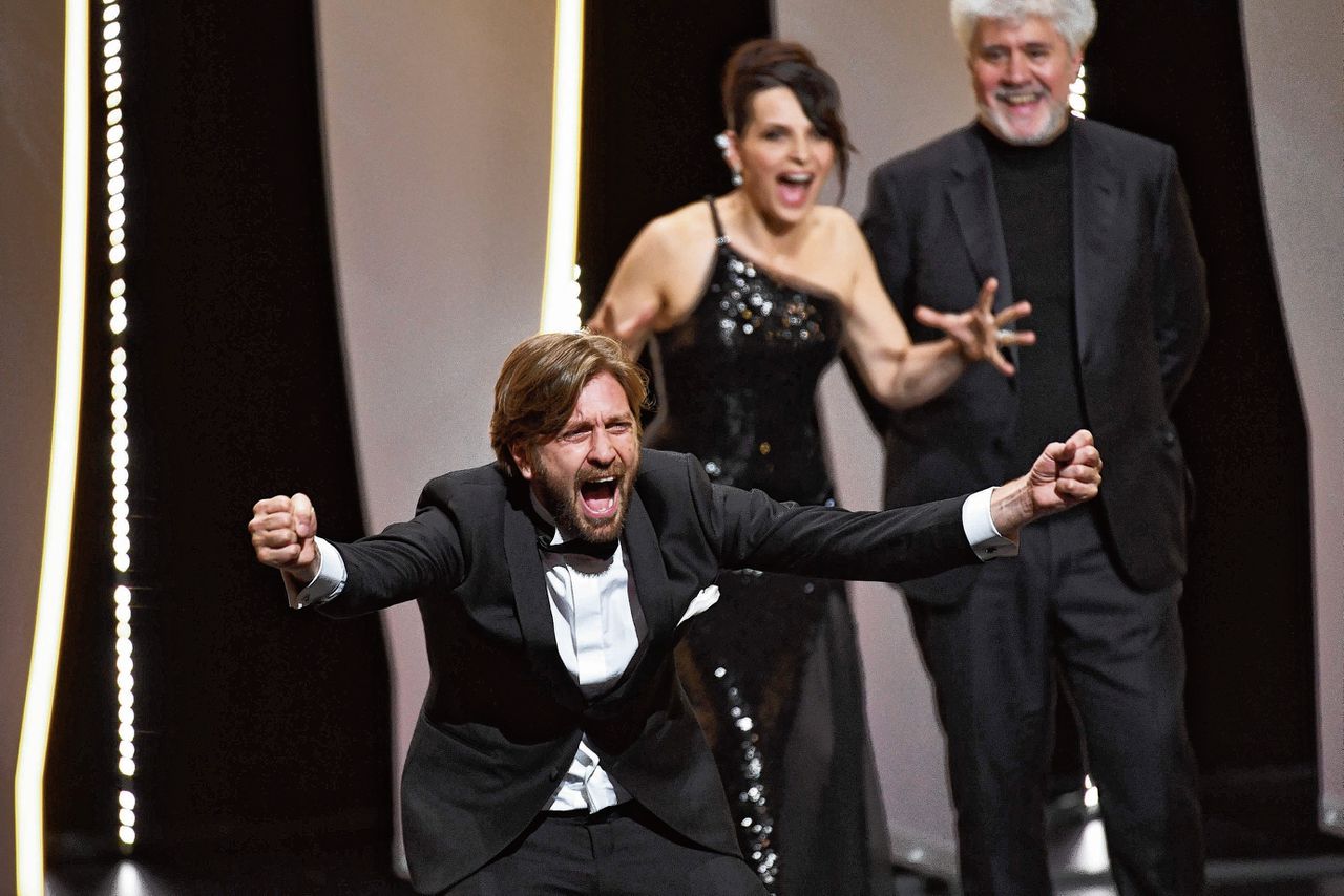 Regisseur Ruben Ostlund schreeuwt zijn geluk uit bij het winnen van de Gouden Palm. Achter hem actrice Juliette Binoche (Rear C) and juryvoorzitter Pedro Almodovar