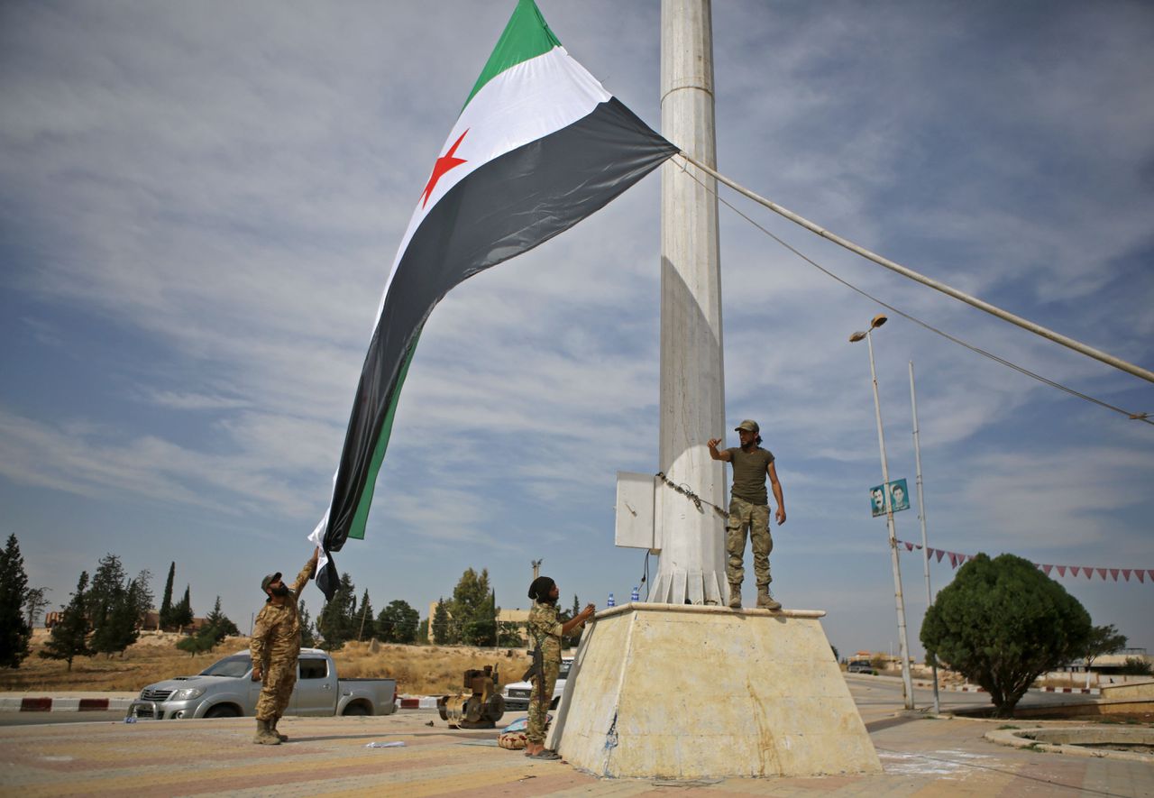 Door Turken gesteunde Syrische rebellen hijsen de vlag van de oppositie in Ayn al-Arus, in de buurt van grens.
