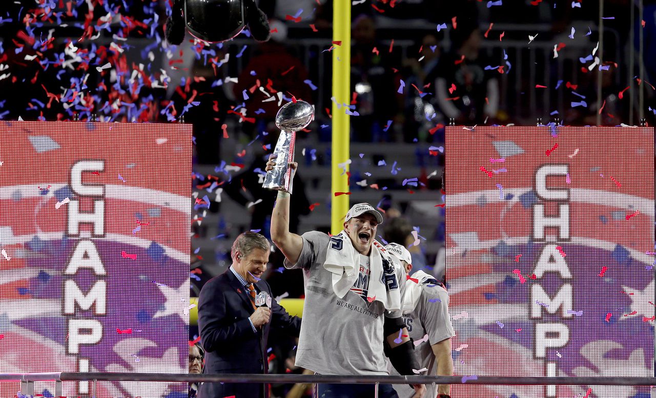 Een speler van de Patriots, de winnaar van Super Bowl, houdt de beker omhoog.