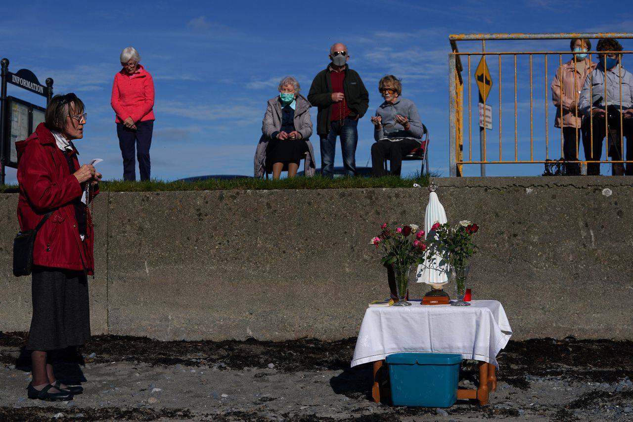 Gelovigen bidden op het strand van het Ierse Ballyloughane voor de slachtoffers van Covid-19.