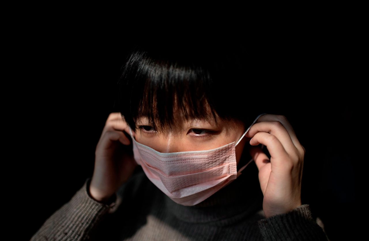 Een 26-jarige vrouw in Beijing bindt een mondkapje voor. Ook in de Chinese hoofdstad is de angst voor het Wuhan-virus sterk toegenomen.