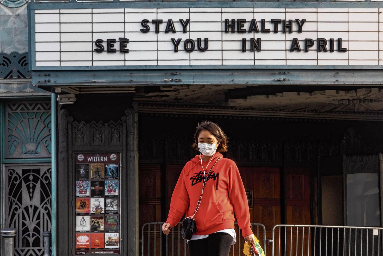 Een vrouw loopt langs een gesloten theater in Los Angeles.