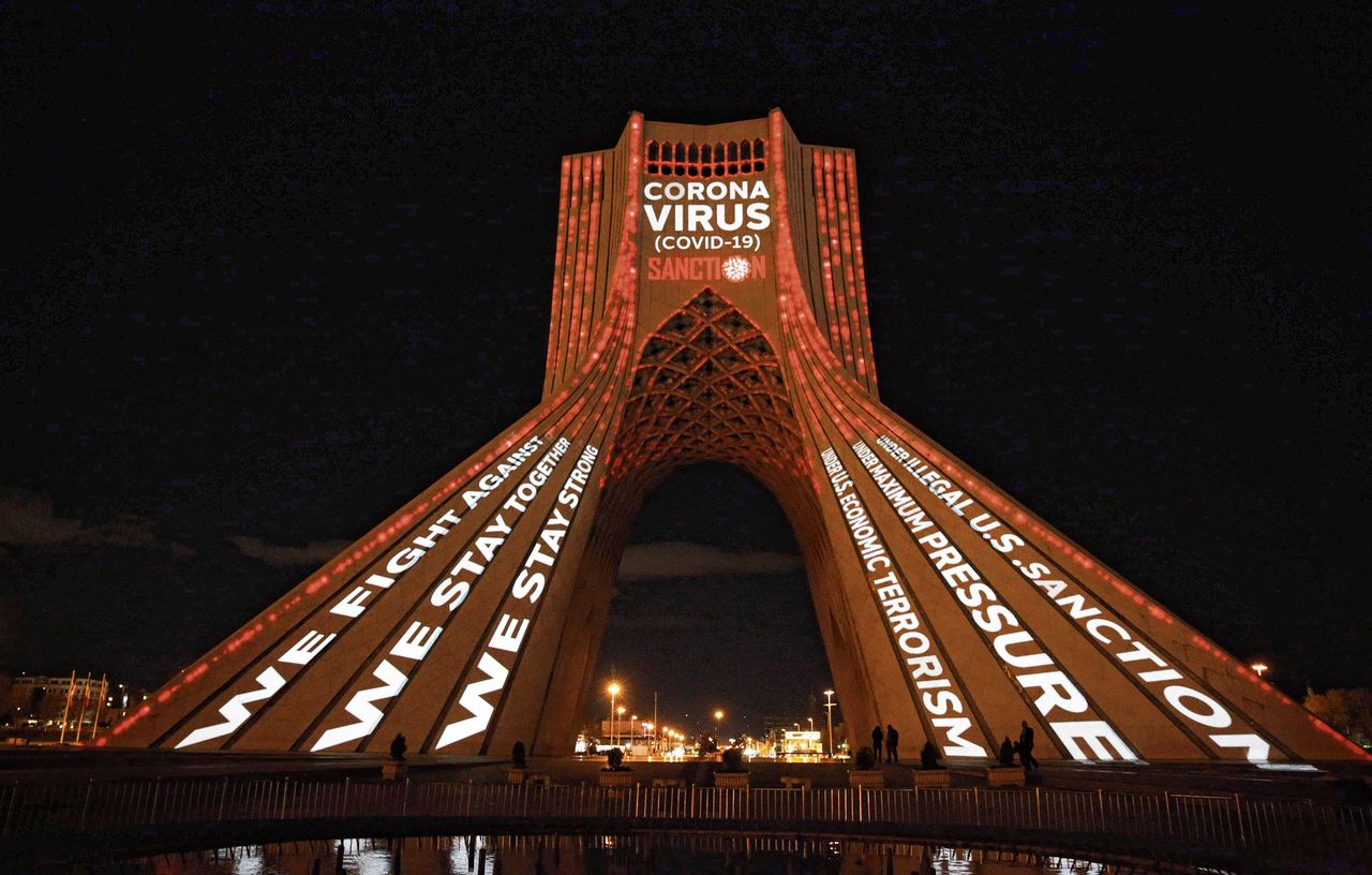 De Azadi Toren in Teheran, verlicht met boodschappen van solidariteit en kritiek op Amerikaanse sancties.