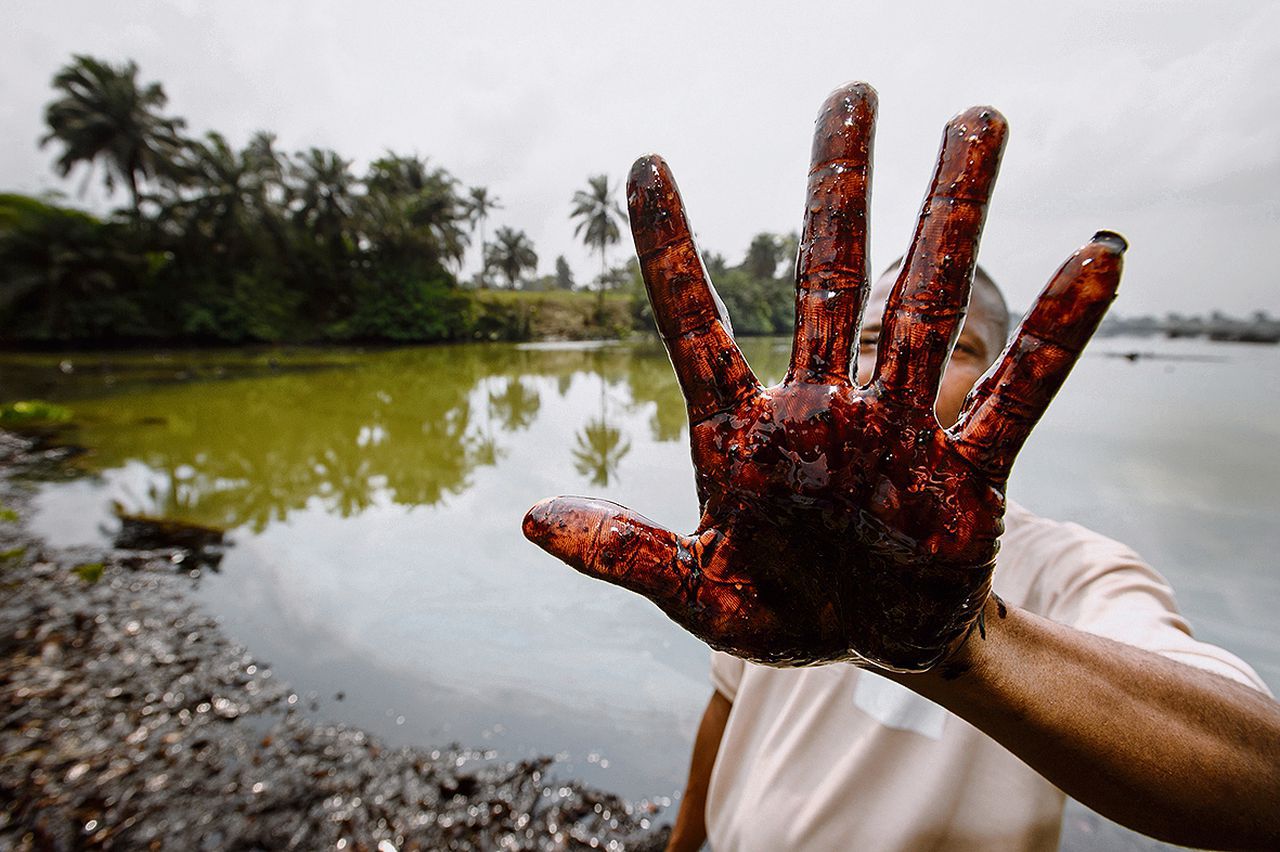 Een Nigeriaan uit Ogoniland toont zijn met ruwe olie besmeurde hand.