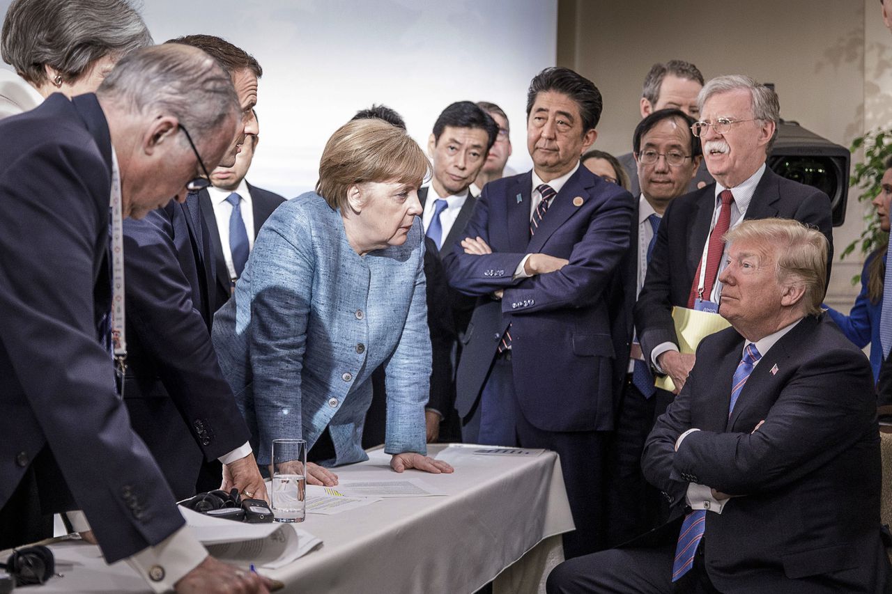 De foto gemaakt tijdens de G7-top in Canada. Met Angela Merkel als de bedrogen vrouw die verhaal komt halen, dominant naar voren leunend.