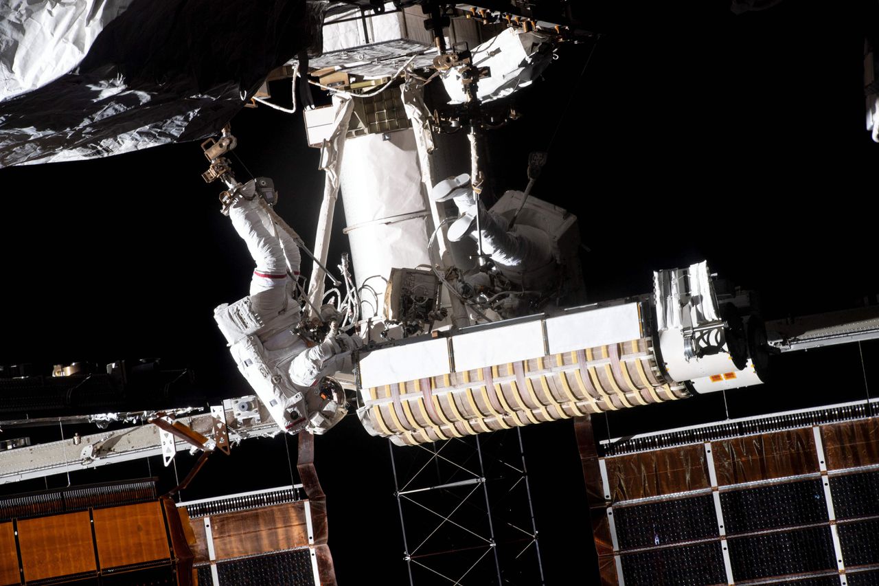 Een Franse astronaut (links) van ESA bevestigt zonnepanelen samen met een Amerikaanse astronaut van NASA om de stroomvoorziening naar de International Space Station (ISS) op te voeren.