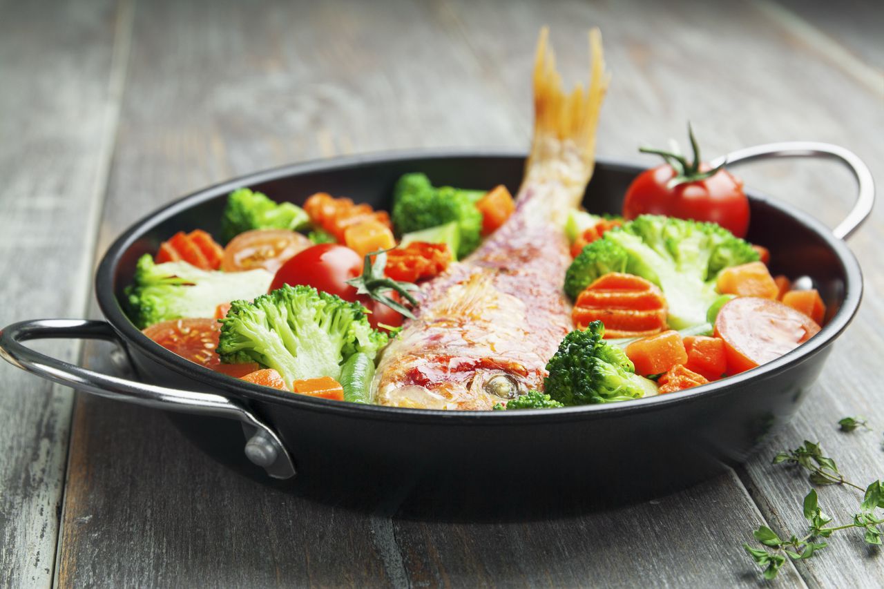 Fried fish with vegetables in the pan