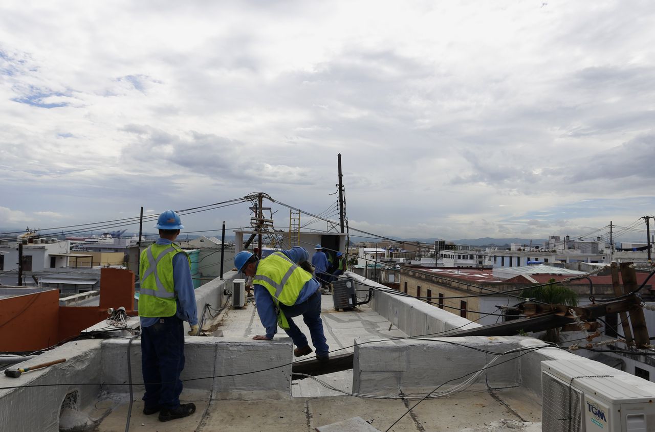 Twee technici zijn bezig met het herstellen van de stroomvoorziening in hoofdstad San Juan.
