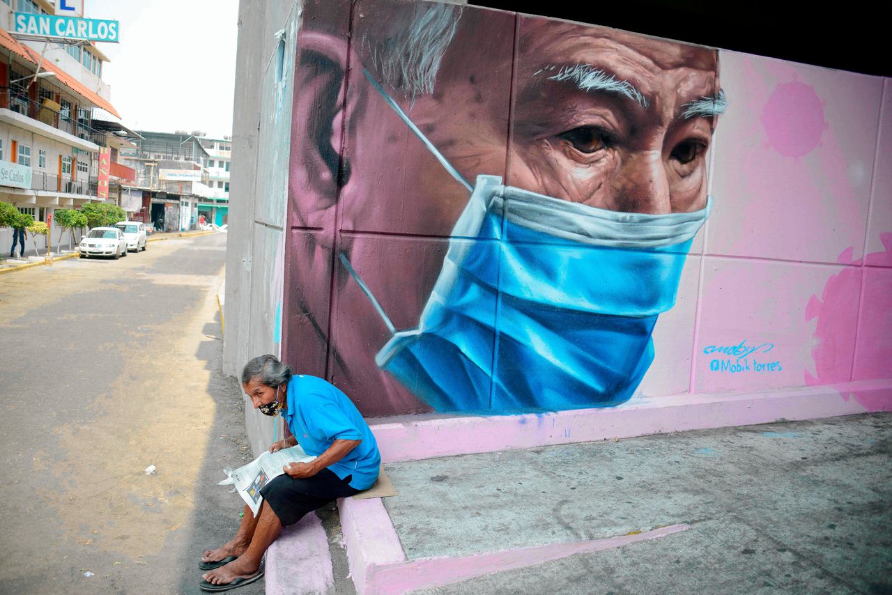 Een man zit naast een muurschildering in Acapulco, Mexico.