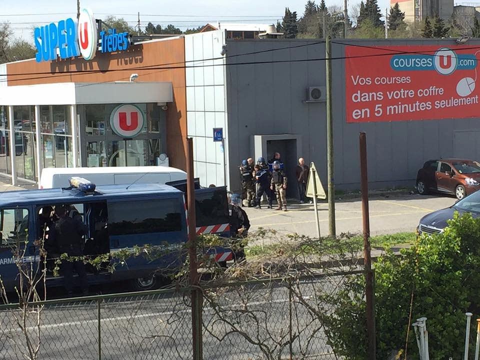 Agenten bij de supermarkt voorafgaand aan de inval.