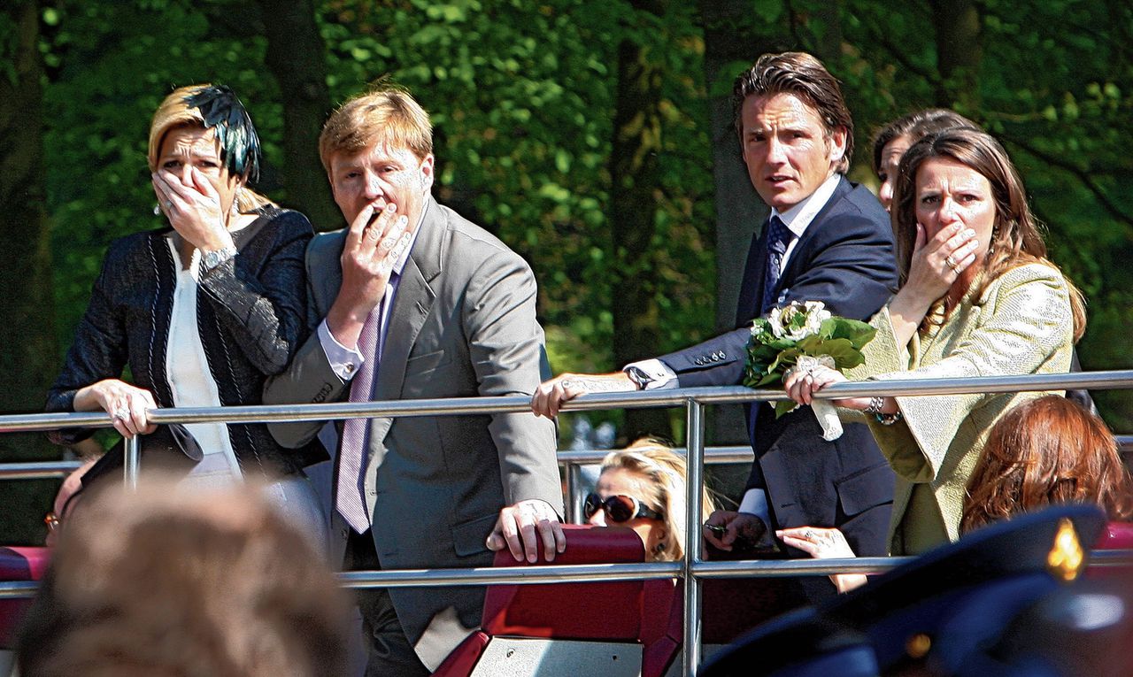 Vlnr: Máxima, Willem-Alexander, prins Maurits en prinses Annette zien vanaf hun bus hoe een auto op het publiek inrijdt.