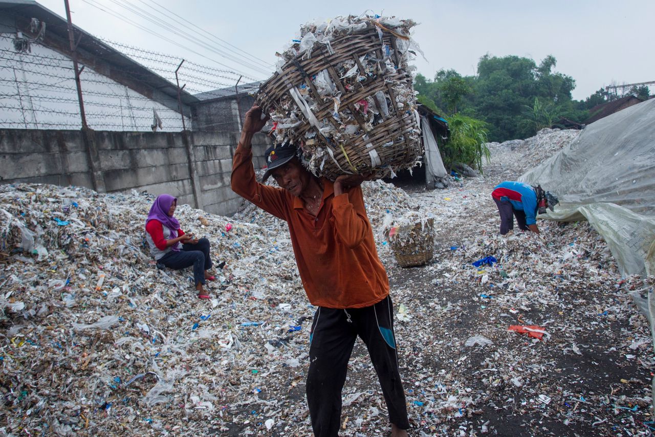 Een man draagt een mand vol plastic afval dat kan worden gerecycled in Bangun, op Java.