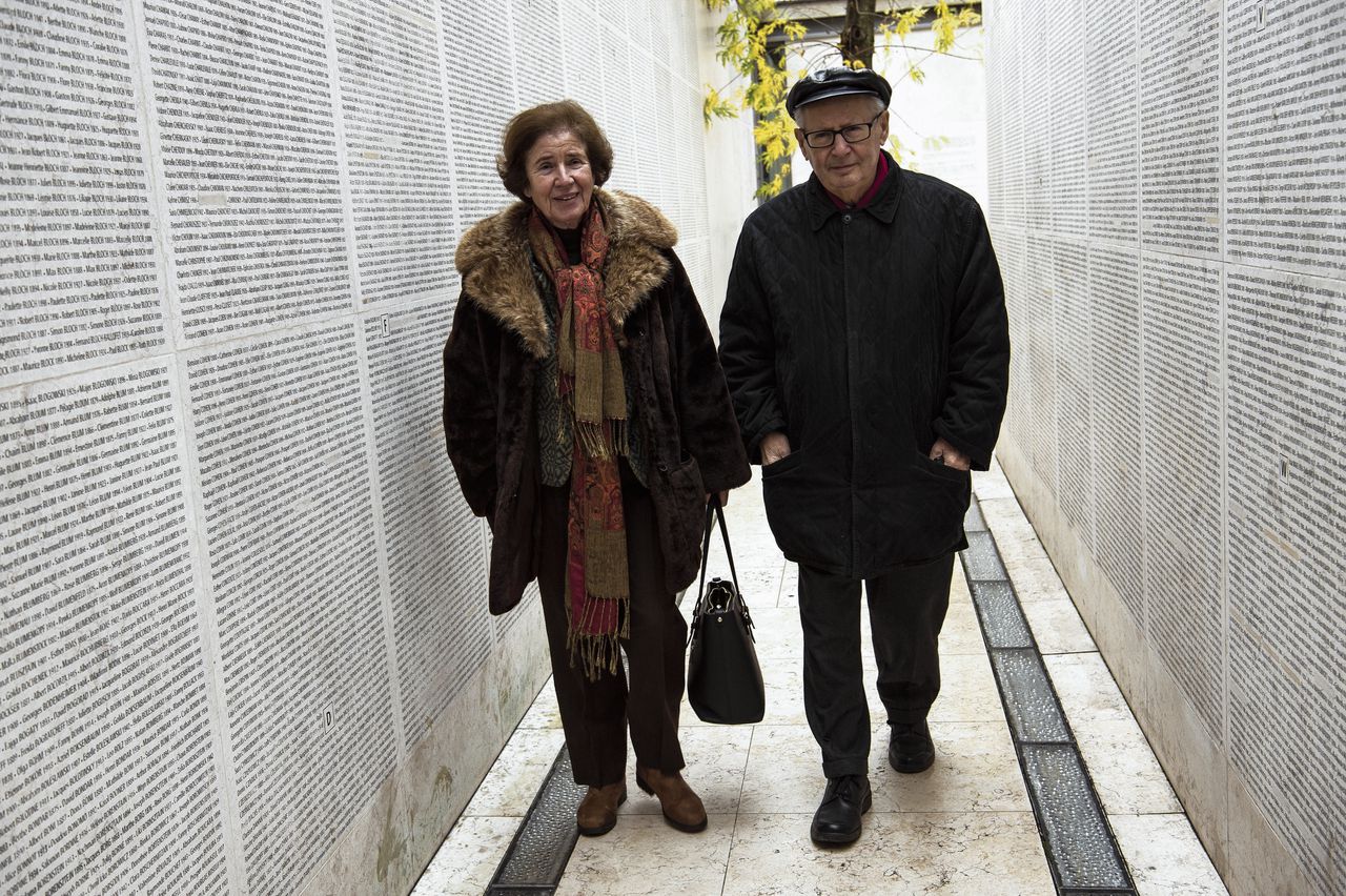 Beate en Serge Klarsfeld lopen langs de Muur van Namen bij het Shoah Monument in Parijs