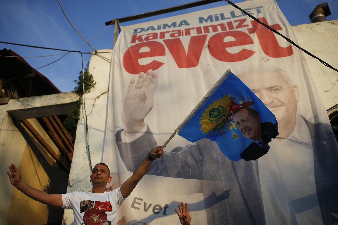 Een aanhanger van Erdogans AK-partij zwaait met een vlag van de president - voor een poster die oproept 'ja' te stemmen.
