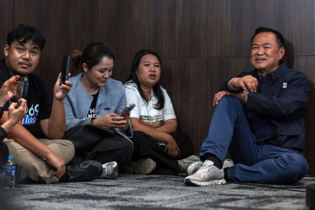 Premier Anutin Charnvirakul zit op de vloer van het hoofdkantoor van zijn partij op verkiezingsdag  in afwachting van een persconferentie 