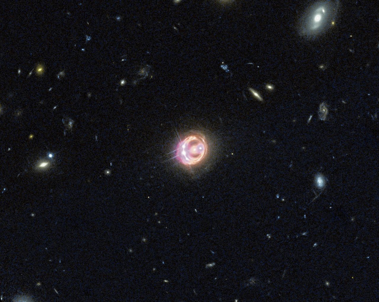 Gecombineerd zichtbaar licht- en röntgenbeeld van systeem RX J1131-1231. De vier ‘diamanten in de ring’ (drie links, één rechts) in het stelsel zijn gravitatielensafbeeldingen van een quasar. Uit vergelijking van de vier afbeeldingen bleek dat het sterrenstelsel biljoenen zwerfplaneten moet tellen.