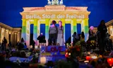 People gather in front of the Brandenburg Gate illuminated with the message „Berlin, city of freedom”, commemorating the victims, after a car rammed into a crowd at the Pride March in Berlin, Sunday, July 26, 2026. (AP Photo/Ebrahim Noroozi)