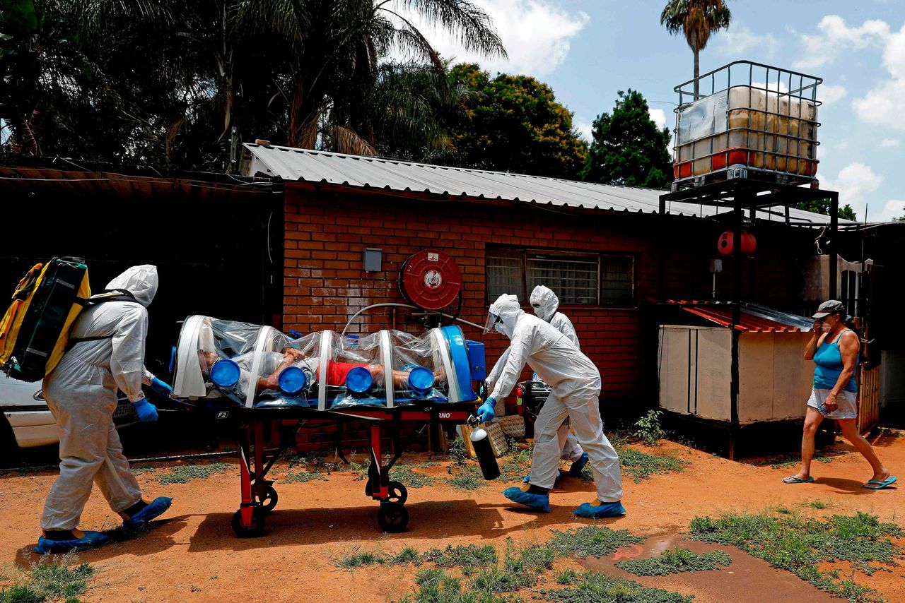 Een man met coronasymptomen wordt door hulpverleners in Pretoria naar een isolatieruimte gebracht.