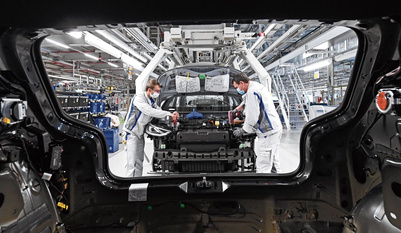 Medewerkers van de Volkswagenfabriek in Zwickau in Duitsland met beschermende kleding. Na een sluiting van vijf weken hervat de Duitse autobouwer maandag de productie.